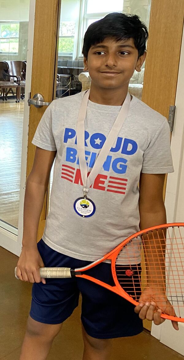 Young Sanjeeva wearing a medal and holding an orange racket